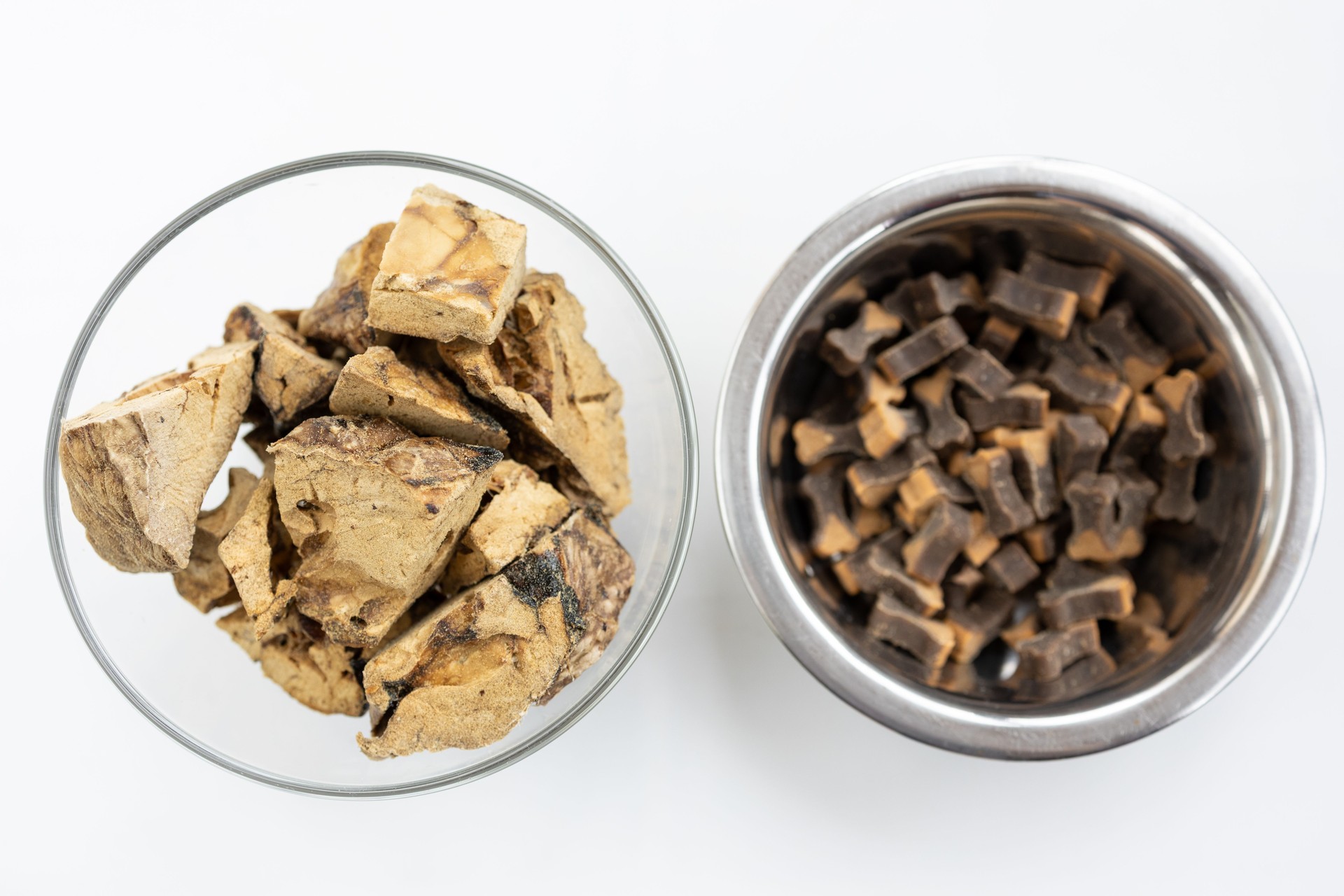 There are different kinds of pet treats in the bowl. Crispy breakfast cereals, chewing gums and pieces of dried meat. For the care of pets and their proper nutrition.